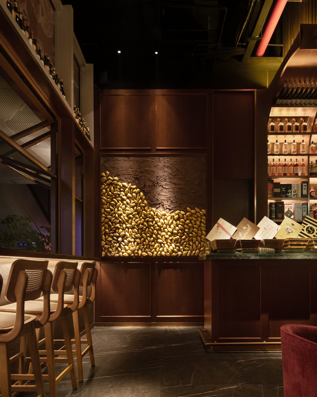 A curved counter with stools along it and warm backlit shelving behind, shot low and dark.