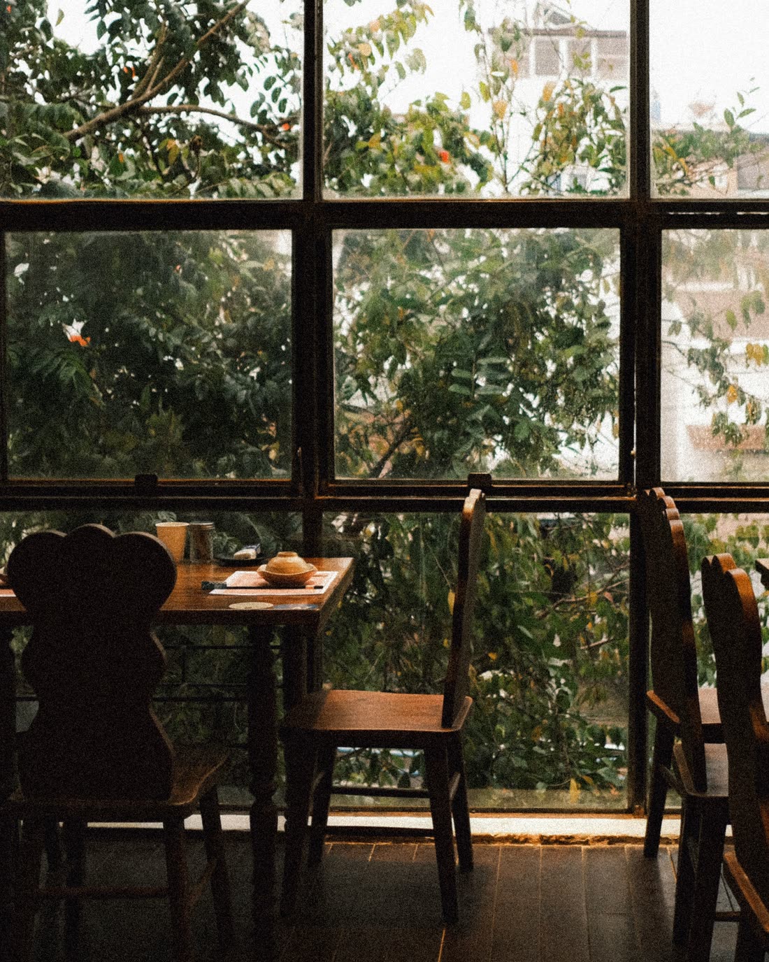 An upper-floor room with tall windows, wooden tables and benches, in flat daylight.